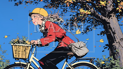 秋の景色：紅葉の小径を自転車を漕ぐ若い女性